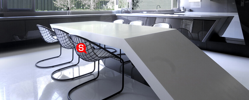 Jadalnia w stylu futurystycznym z białym stołem w nowoczesnym kształcie. Wokół niego stoją metalowe, czarno-białe krzesła o designerskiej formie.